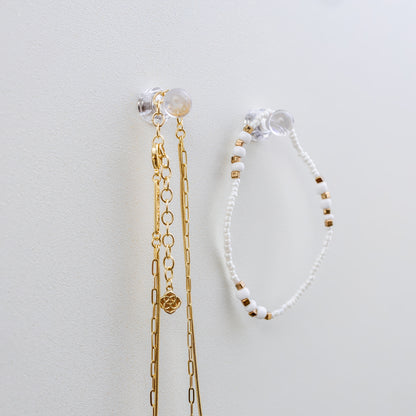 Clear mini magnets that hold jewelry on a shimmer pearl metal board that is a magnetic board for holding jewelry and doubles as a memo board